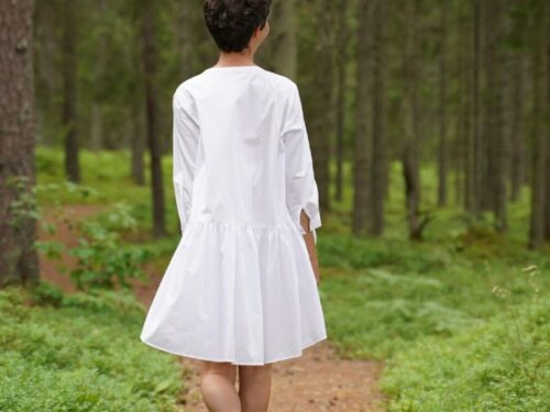 Paljajalu naine valges kleidis kõnnib metsarajal.