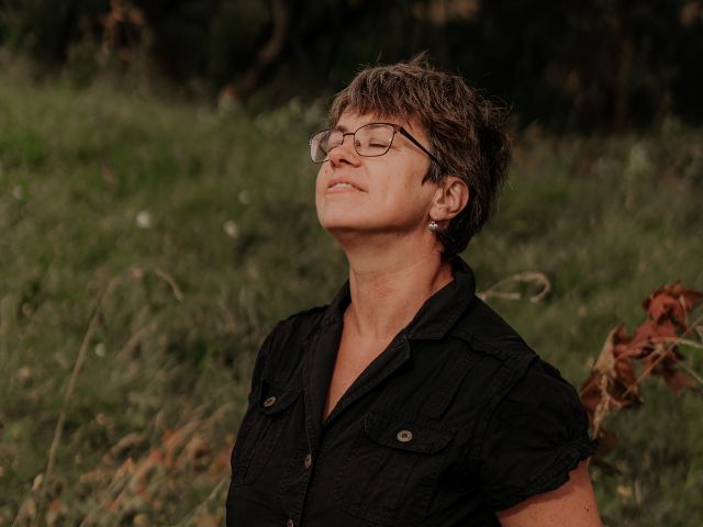 Naine suleb silmad ja hingab rahulikult looduses, sümboliseerides sisemist rahu ja ühendust iseendaga läbi une.