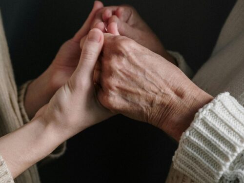 Kaks inimest hoiavad üksteise käsi – toetuse ja hoituse sümbol