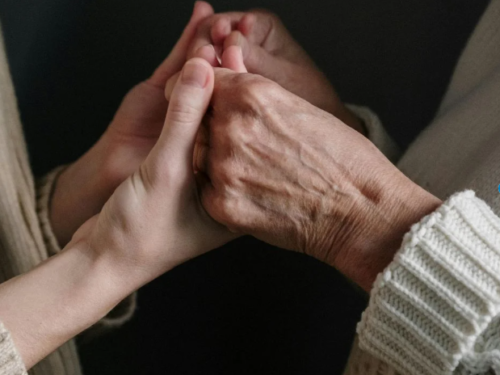 Kaks inimest hoiavad üksteise käsi – toetuse ja hoituse sümbol.